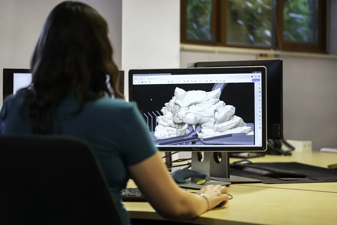 Una mujer, de espaldas, revisa un modelo 3D en la pantalla de su computador en una oficina